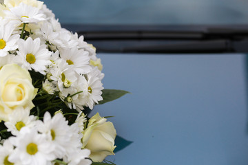 A wedding day, flowers placed on a hood from a car in which the young woman will be