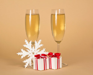 Festive drink in glasses, boxes with gifts and snowflake on beige