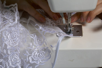 A woman works on a sewing machine. Sewing of lace fabric.