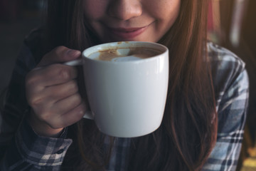Closeup image of Asian woman smelling and drinking hot coffee with feeling good in cafe