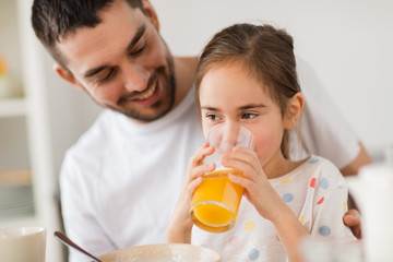 happy girl with father drinking juice at home
