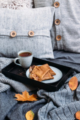 Breakfast with pancakes and tea. Autumn concept of the morning with warm clothes