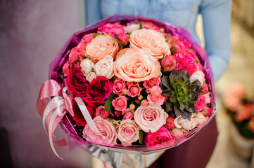 Large and gorgeous pink bouquet of flowers with a succulent in womans hands