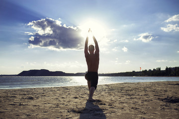 Fototapeta na wymiar man practices yoga and meditates in the sport position on the beach