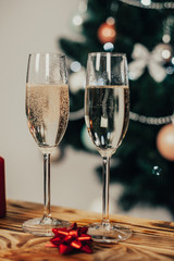 Two glasses of champagne on the background of a Christmas tree with candles with snow