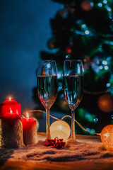 Two glasses of champagne on the background of a Christmas tree with candles in darkness with snow