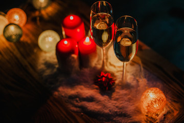 Two glasses of champagne on the background of a Christmas tree with candles in darkness with snow