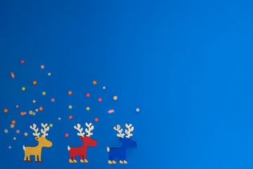 Сolorful reindeers on the edge of blue background