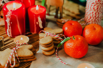 Traditional christmas ginger cookies on woofen background with cutters, candles and red rope. 