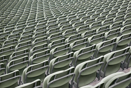 Sitzreihen grüner Plastikstühle in einem Stadion, von hinten gesehen