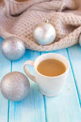 New Year's silver balls on a blue wooden background with a cup of hot tea or coffee and with a knitted scarf