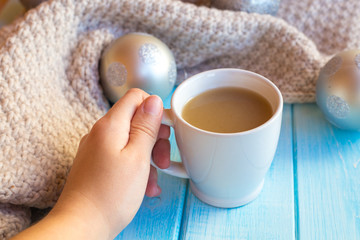 New Year's silver balls on a blue wooden background with a cup of hot tea or coffee and with a knitted scarf