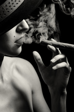 Junge Frau mit Hut raucht eine Zigarre