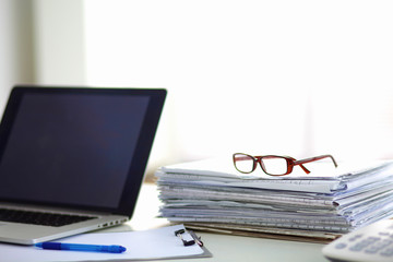 Laptop with stack of folders on table on white background