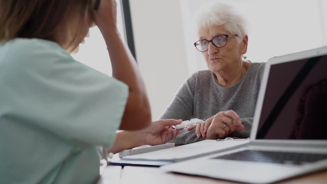Nurse giving prescription to elderly woman