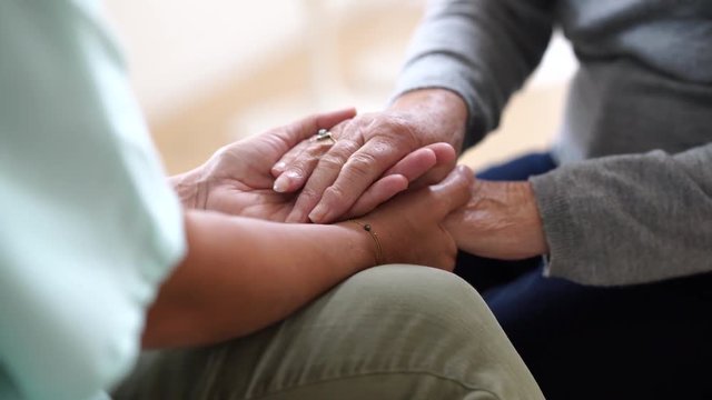 Closeup of nurse holding old woman hands