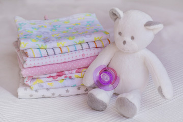 Stack of baby diapers and teddy  bear plush toy