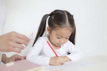 Attractive Little Girl writing Book. Dad Teaching her at home. Children Lifestyle, Education Concept.