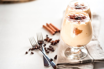 Exquisite Italian dessert tiramisu in cognac glasses on a white