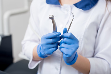 Dentist with blue gloves holding dental equipment at the dental office. Close-up, selective focus on tools. Dentistry