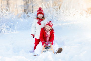 Obraz na płótnie Canvas Kids play in snow. Winter sleigh ride for children