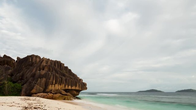 A static early morning timelaspe on the famous beach of Anse Grosse Roche (a massive granitic rock) on La Digue island, Seychelles with overcast weather clearing up as the sun peaks through. 