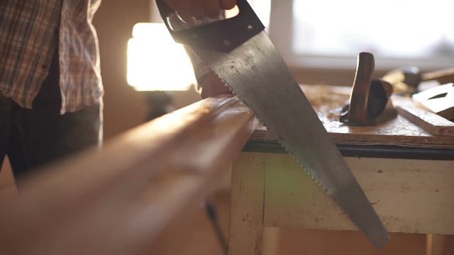 A man sawing wood Board with hand saw. Macro. Slow motion