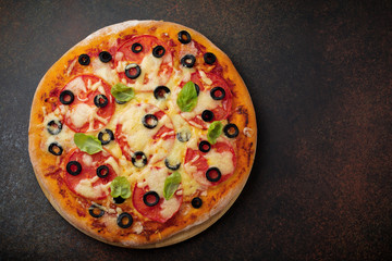 Pizza margarita with tomatoes, mazarella and slices of olives on a dark concrete or stone background. Traditional Italian cuisine. Selective focus. Top view.