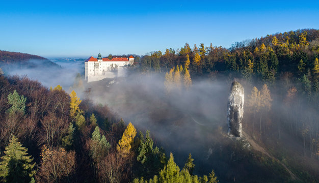 Limestone cliff Pieskowa Skala near Krakow, Poland, with isolated rock  &ldquo;Maczuga Herkuklesa&rdquo; (Hercules cudgel or bludgeon) and historic Renaissance castle in morning fog in fall. Aerial panorama