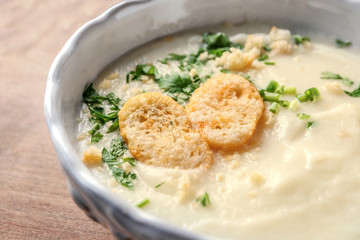 Bowl of yummy potato soup with croutons on wooden table