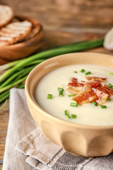 Bowl of yummy potato soup with bacon on wooden table