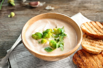 Bowl of yummy potato soup with broccoli on wooden table