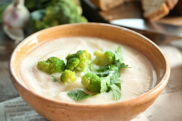 Bowl of yummy potato soup with broccoli on wooden table