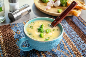 Cup of yummy potato soup with broccoli on table