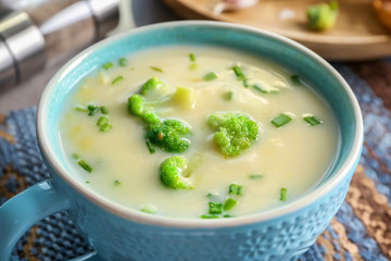 Cup of yummy potato soup with broccoli on table