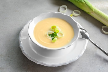 Bowl of yummy potato soup with leek on table