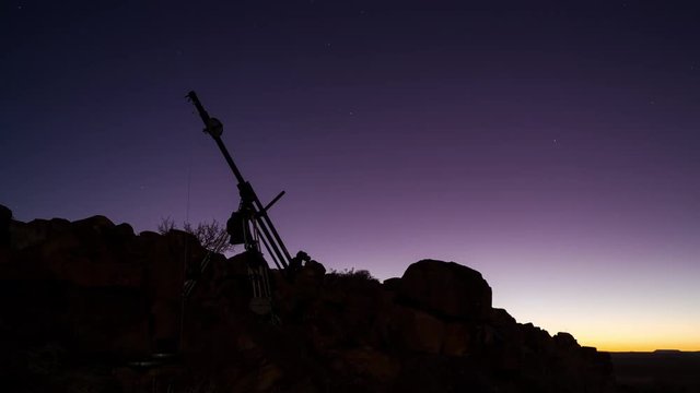 A night time timelapse of a motorised filming jib on a rocky, barren moonlit landscape in the Karoo, with Dolomite rock boulders in the foreground, behind the scenes, BTS. 