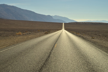 Fototapeta na wymiar Long road through Death Valley National Park heading toward Bad Water