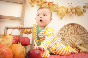 Fototapeta premium Adorable baby in striped pajamas and basket with apples indoors