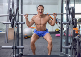Fototapeta premium Muscular man training with barbell in gym