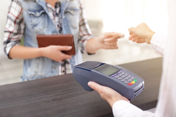 Woman using bank terminal for credit card payment indoors