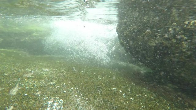Underwater view of a wave crashing in shallow water over corals and rocks at Mah_, Seychelles. GoPro, POV. 