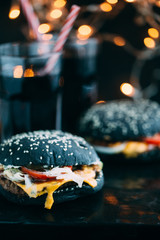 Black burger with meat, cheddar cheese and vegetables. Rustic style