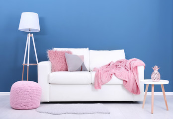 Comfortable sofa on color wall background