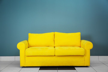 Comfortable sofa on color wall background