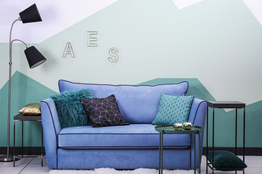 Comfortable sofa on color wall background