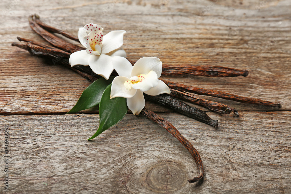 Sticker dried vanilla pods and flowers on wooden background