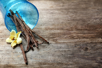 Dried vanilla pods and flower on wooden background