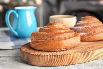 Wooden board with sweet cinnamon rolls on table
