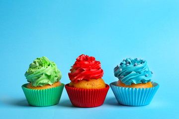 Tasty colorful cupcakes on color background
